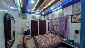 Un dormitorio con cama, sofá, televisión y espejo.