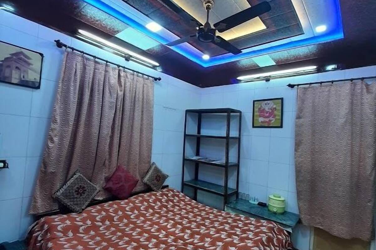 Ein Schlafzimmer mit Bett, Vorhängen, Deckenventilator und Ablagefläche.
