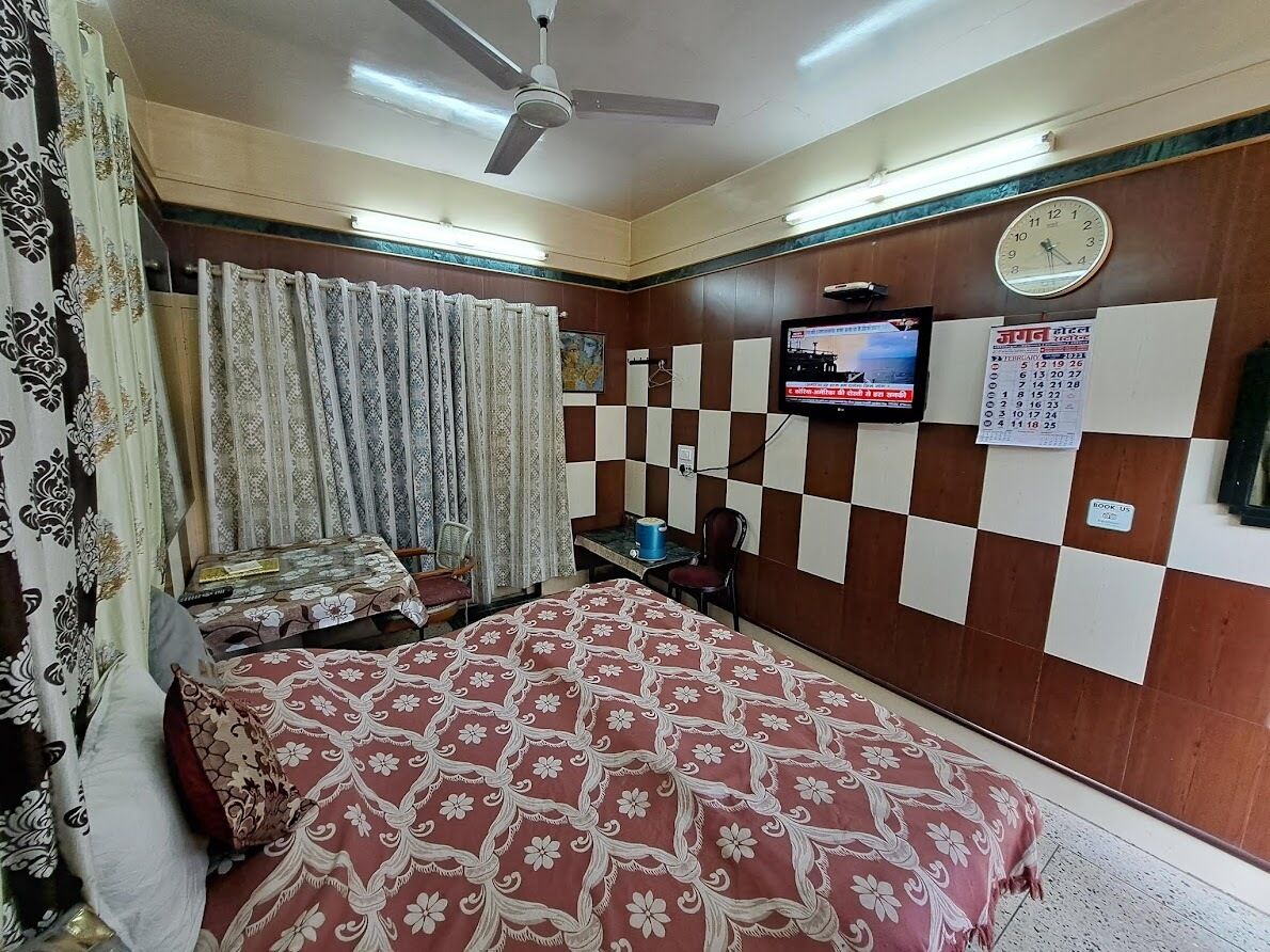 A hotel room with a bed, a television, a calendar, and a ceiling fan.