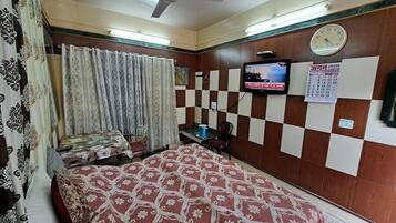 A hotel room with a bed, a television, a calendar, and a ceiling fan.