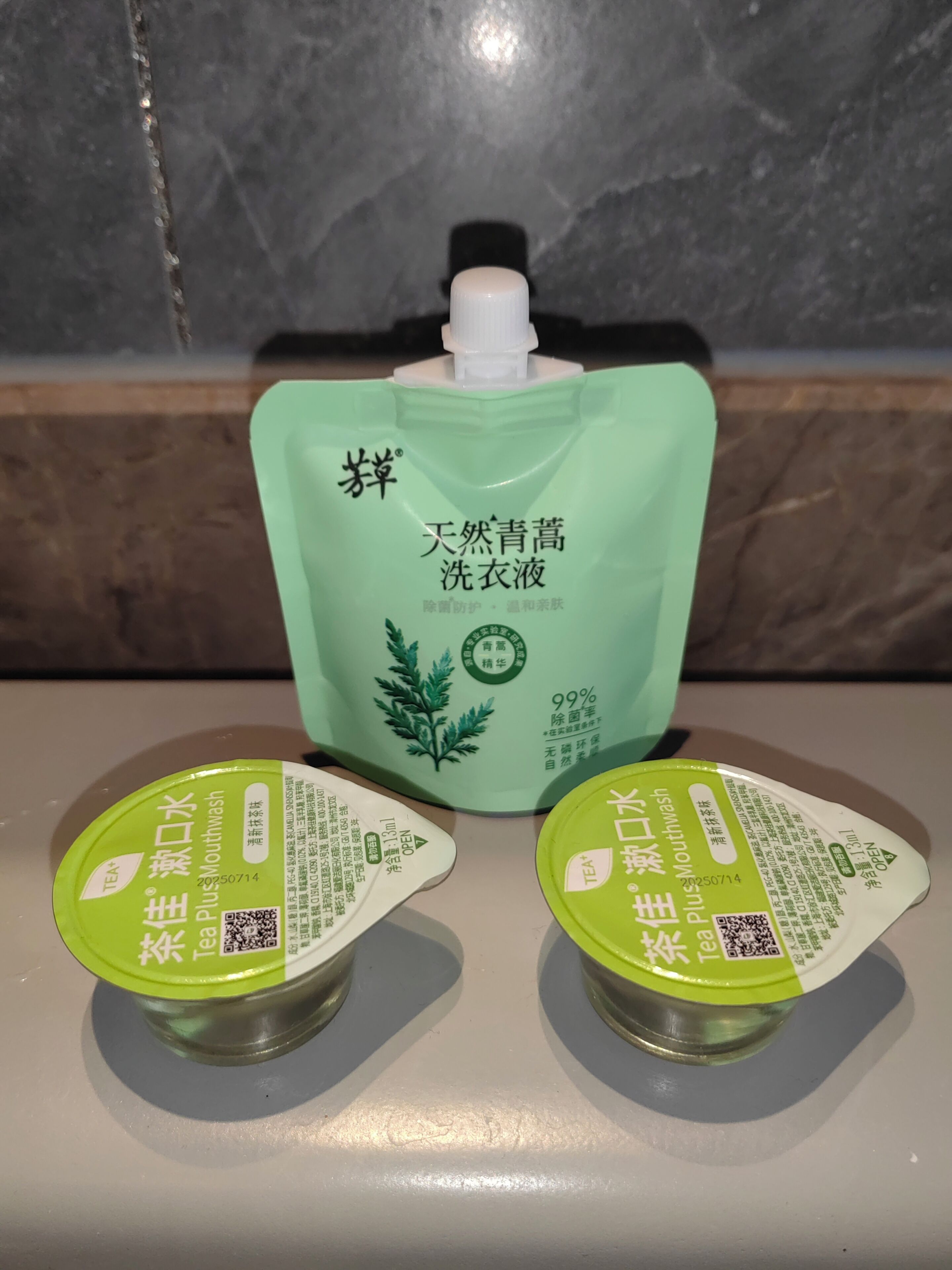 A green bottle of mouthwash and two containers of tea on a countertop.
