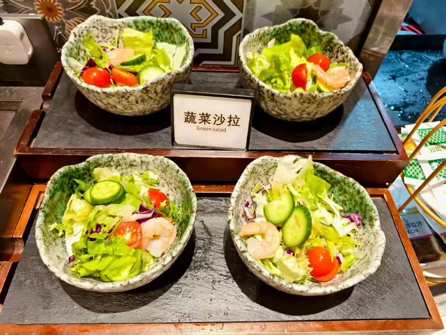 Drei Schüsseln mit grünem Salat, mit einem Schild mit der Aufschrift 'Grüner Salat'.