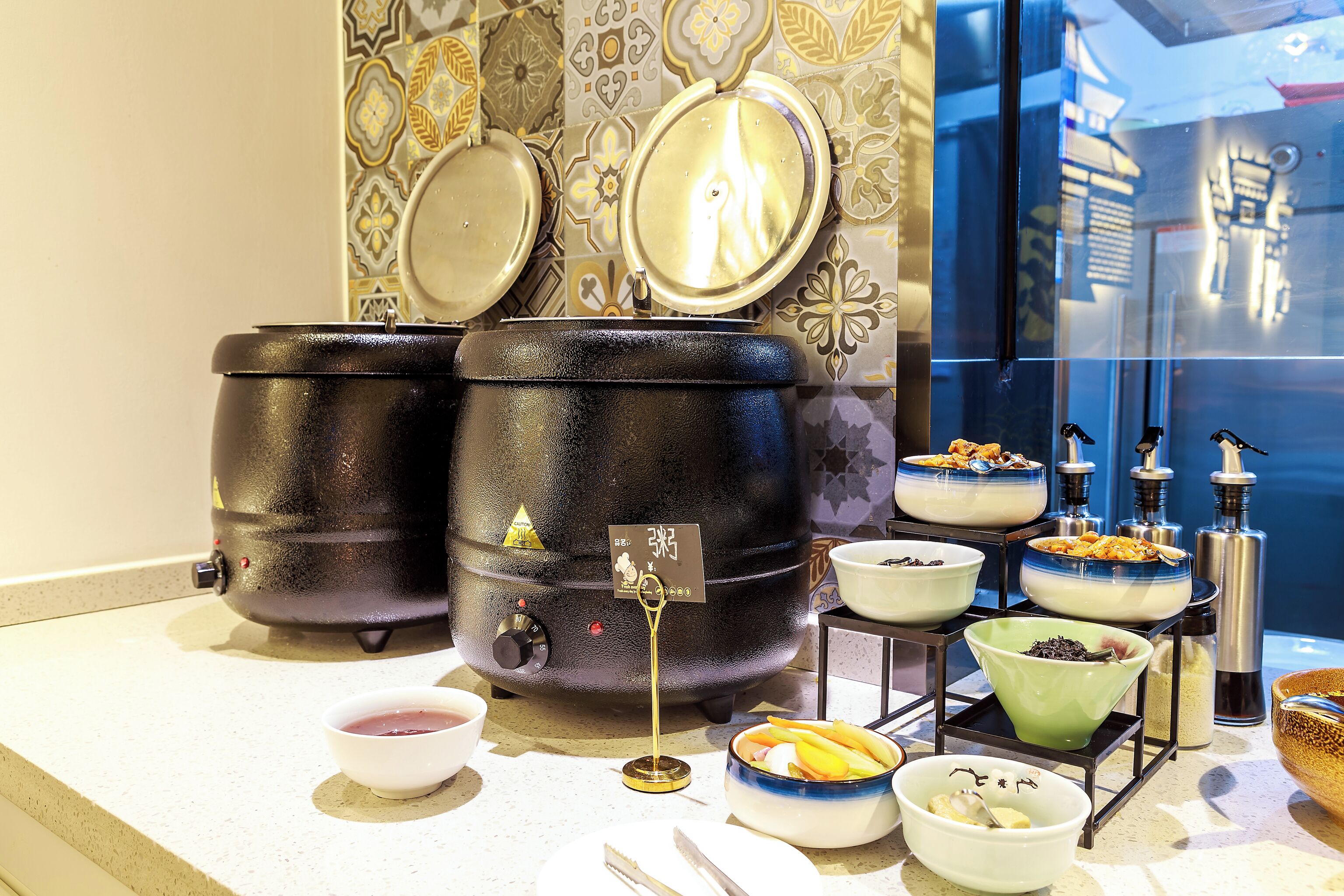 A kitchen counter with two large black containers, various bowls with food, and condiments.