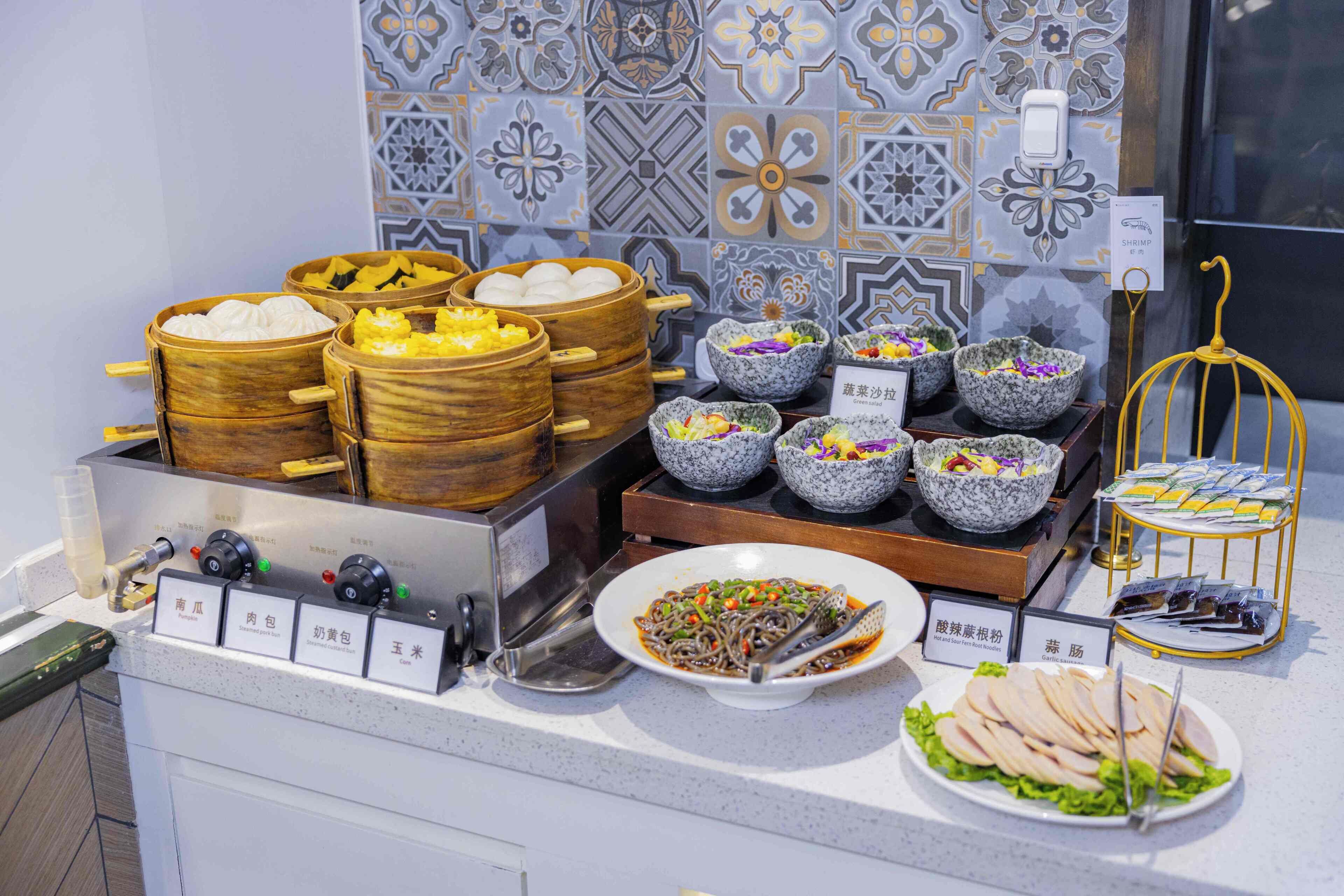 A buffet with various food options, including dumplings, salads, and noodles.