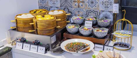 A buffet with various food options, including dumplings, salads, and noodles.