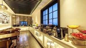 Een moderne hotellobby met een buffetgedeelte, zitplaatsen en een groot raam.