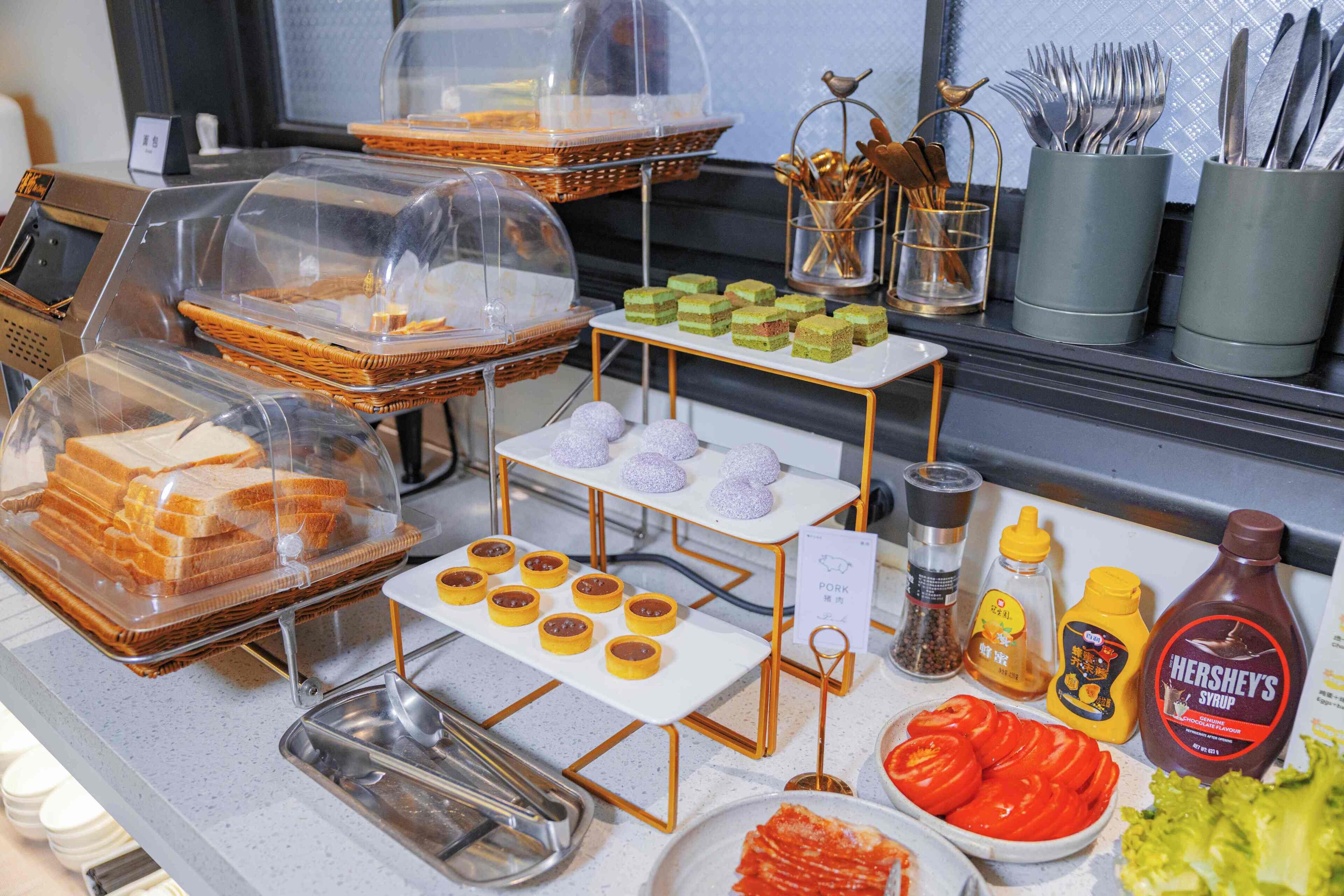 A buffet with various food items, utensils, and condiments.