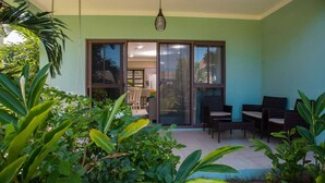 Un patio con zona de comedor, puertas corredizas de vidrio y abundante vegetación.