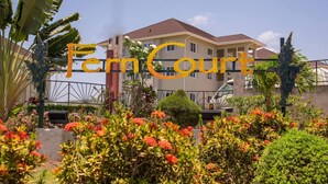 A hotel with a sign reading "Ferm Court" in front of a building with multiple floors and a red roof. - EN CASA @ Richmond Estate (Priory)