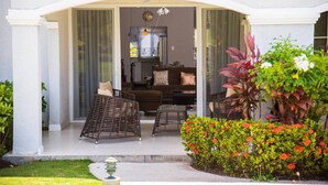 A covered outdoor seating area with wicker furniture, a small table, and a potted plant. - EN CASA @ Richmond Estate (Priory)