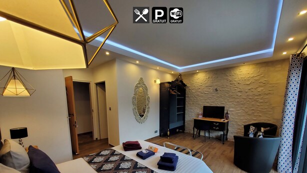 A modern hotel room with a large bed, a desk, a TV, and a wardrobe. - Appart'é Nature l'ESCALE - SAINTES (Chaniers)