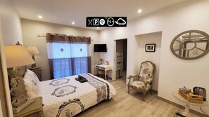 A hotel room with a bed, a desk, a chair, a TV, and a wall-mounted mirror. - Appart'é Nature l'ESCALE - SAINTES (Chaniers)