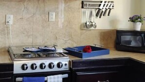 Une cuisine avec des meubles de rangement en bois foncé, une cuisinière à gaz, un four à micro-ondes et un porte-couteaux.