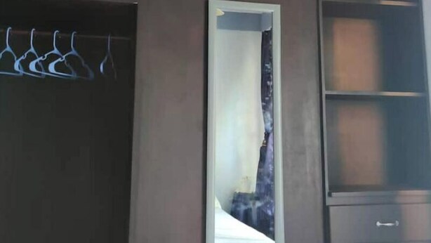 Une chambre avec une armoire, un miroir et un ventilateur de plafond.
