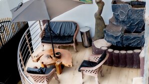 A circular outdoor seating area with a cushioned bench, a small table with a drum, and a decorative stone structure. - ADESHIE FIE HOTEL (Tarkwa)