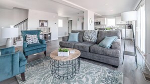 A modern living room with a grey sofa, teal armchairs, and a coffee table. - Quaint house on the bluffs overlooking the  scenic Missouri River. (Atchison)