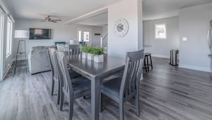 A modern dining area with a wooden table, grey upholstered chairs, and a potted plant centerpiece. - Quaint house on the bluffs overlooking the  scenic Missouri River. (Atchison)
