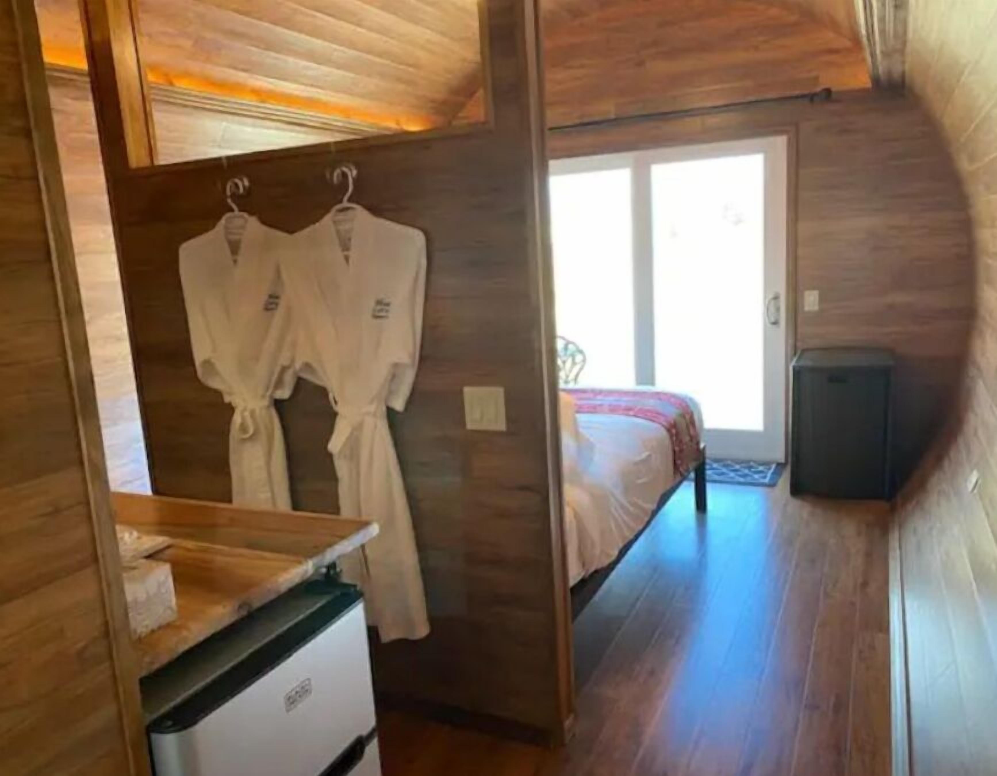 Una habitación compacta con cama, una kitchenette pequeña y techo de madera.