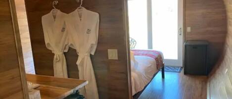 Una habitación compacta con cama, una kitchenette pequeña y techo de madera.