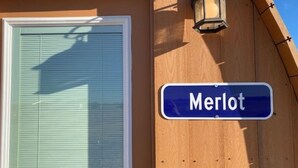 Uma placa de rua com o nome 'Merlot' em um prédio de madeira.