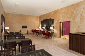 A hotel lobby with a dining area, a reception desk, and a large wall-mounted artwork. - Wyndham Baku (Baku)