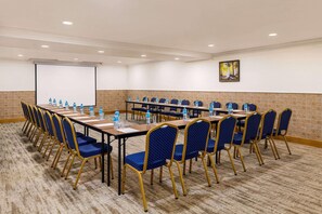 A conference room with long tables, blue chairs, and water bottles. - Wyndham Baku (Baku)
