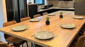Eine moderne Küche mit einem Holzespeisetisch, gedeckt für sechs Personen, mit Tellern, Gläsern und Besteck.