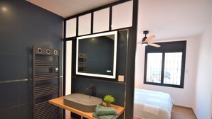 Ein modernes Badezimmer mit integriertem Waschbecken, einem Spiegel und einem Deckenventilator.