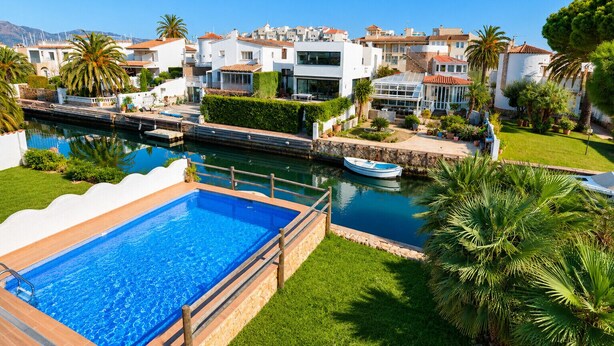 Ein Wohngebiet mit einem Swimmingpool, einem Boot und Häusern mit roten Ziegeldächern.