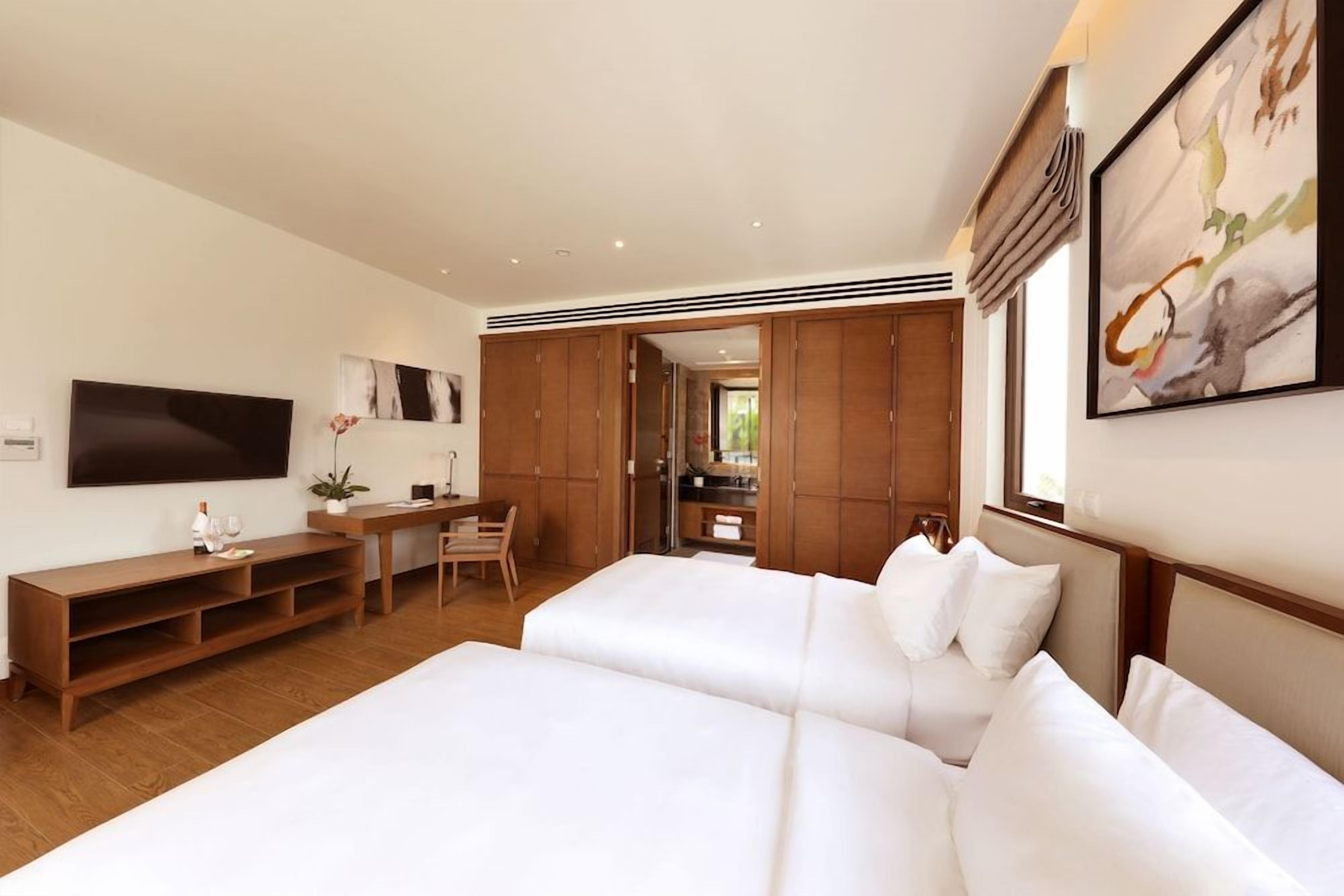 Habitación de hotel con una cama grande, un escritorio y un televisor montado en la pared.