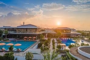A hotel with a swimming pool, outdoor seating, and a sunset view. - Ascott Oakwood HA Long (Ha Long)