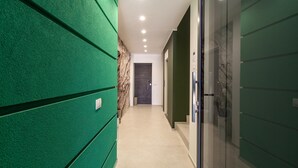 Un pasillo con paredes verdes, una pared de mármol y una puerta al final.