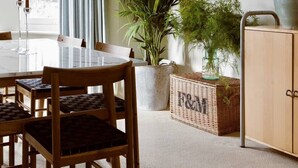 Un coin repas avec une table, des chaises et une grande plante en pot.