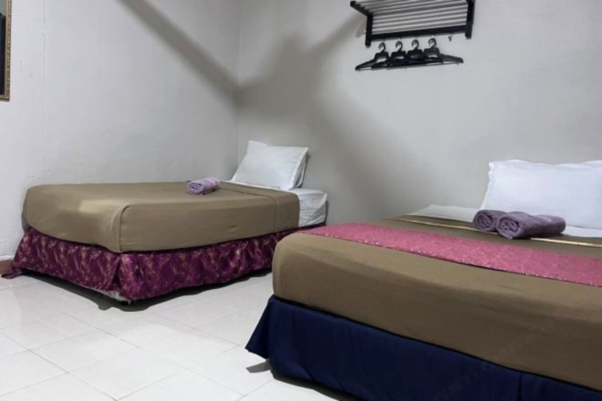 Hotellihuone, jossa on kaksi sänkyä, ja jokaisessa sängyssä on erivärinen peitto ja tyyny.