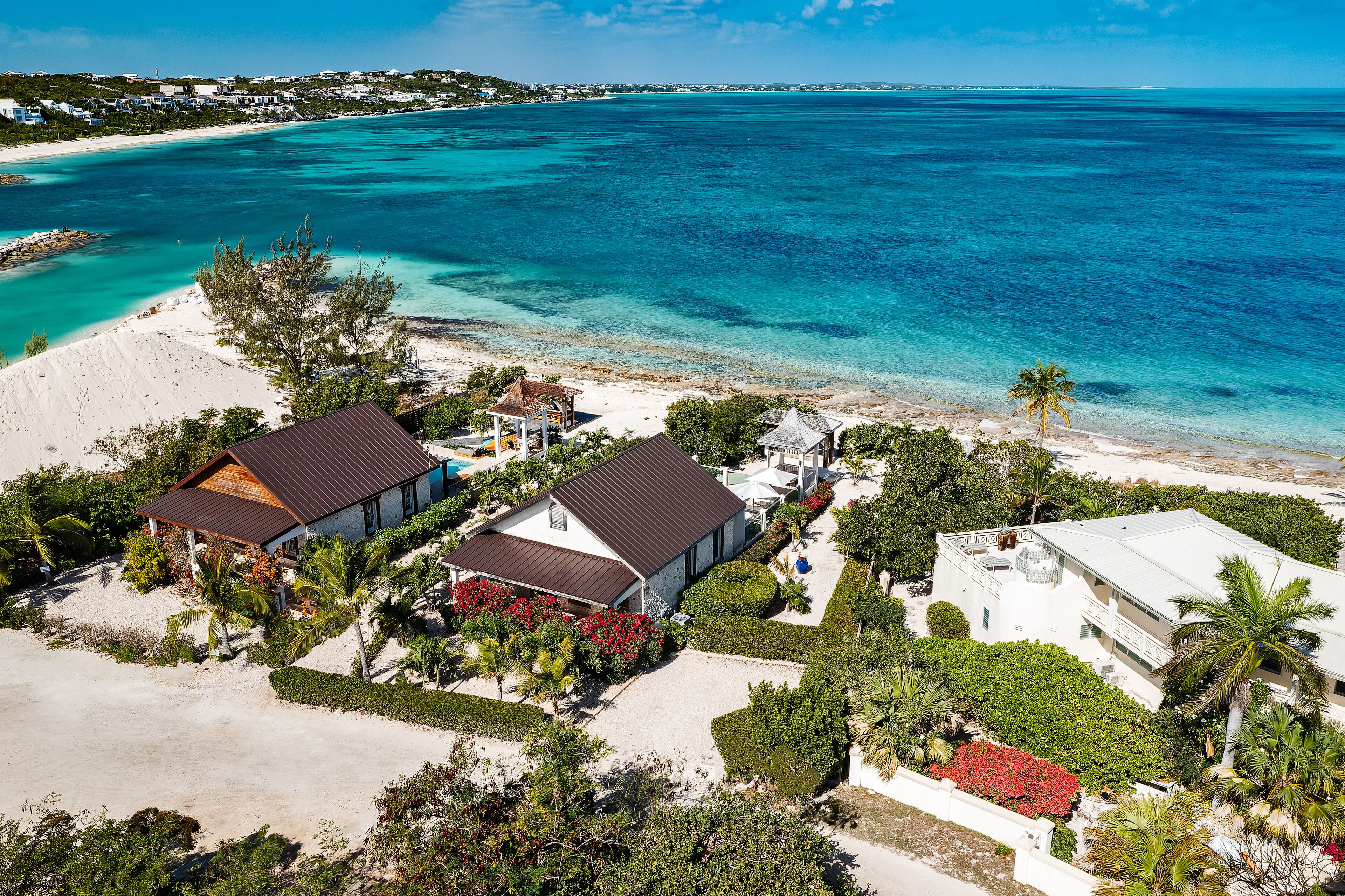 A coastal property with multiple buildings, a sandy beach, and a view of the ocean.