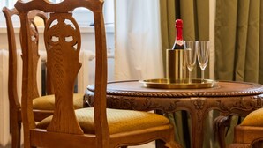 A wooden dining table with a bottle of champagne and two glasses, set on a patterned carpet.
