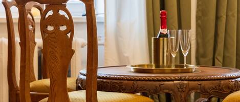 A wooden dining table with a bottle of champagne and two glasses, set on a patterned carpet.