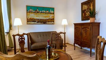 Uma sala de estar com um sofá, duas luminárias, um quadro, um aparador e uma garrafa de champanhe em um suporte.