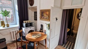 A compact kitchen with a washing machine, a microwave, and a small dining table with chairs.