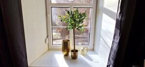 Una ventana con una planta y dos jarrones decorativos en el alféizar.
