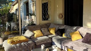 A modern living room with a sectional sofa, a coffee table, and a large window overlooking a garden.