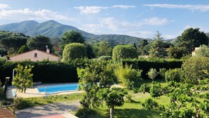 A residential area with a swimming pool, lush greenery, and mountains in the background.