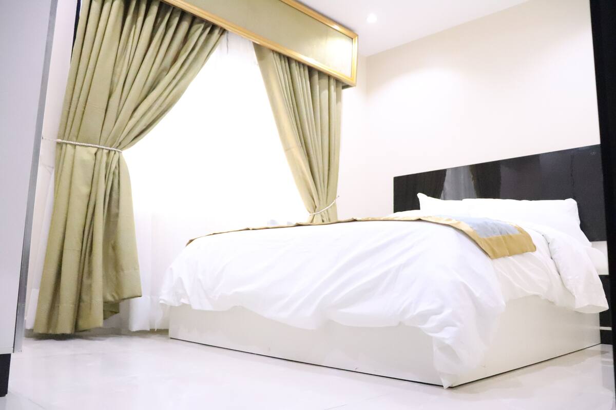 A modern bedroom with a large bed, white bedding, and a headboard.