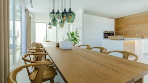 Un comedor moderno con una larga mesa de madera, sillas de madera y lámparas colgantes.