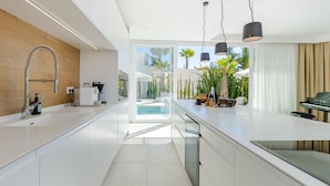 Una cocina moderna con una isla grande, un lavaplatos empotrado e iluminación colgante.