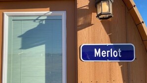 A street sign reading "Merlot" mounted on a wooden building. - Riesling  Cabin (Seguin)