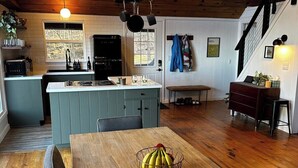 Una cocina acogedora con una isla central, suelo de madera y una lámpara colgante.