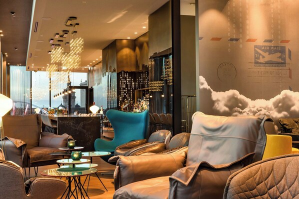 A modern lounge area with leather seating, a bar, and a cityscape view.