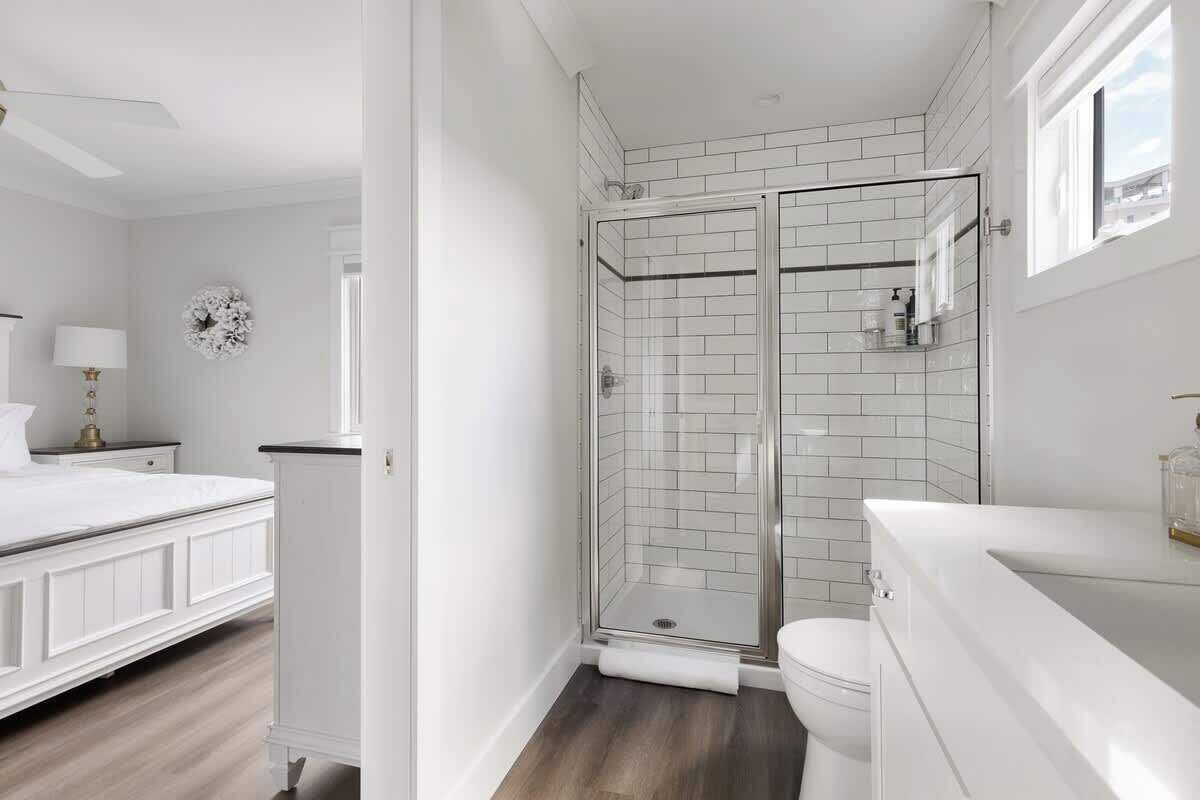 A bathroom with a glass shower enclosure, a toilet, and a white sink.