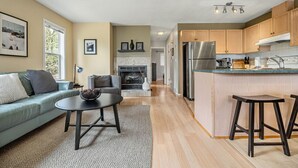 A modern kitchen with wooden cabinets, a stainless steel refrigerator, and a built-in island with stools.